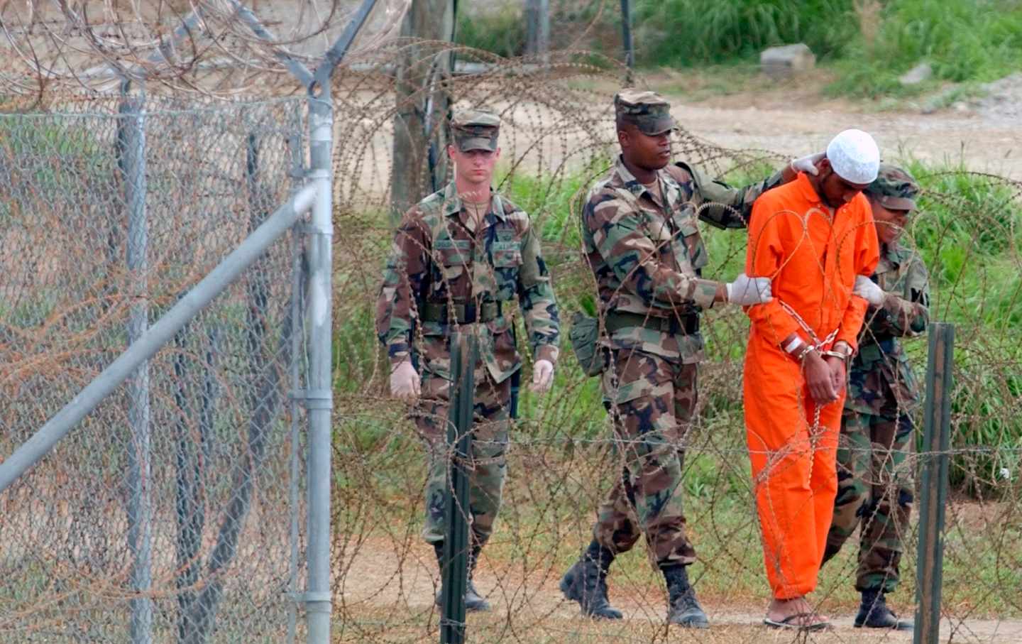 soldier leads prisoner in Guantnamo Bay